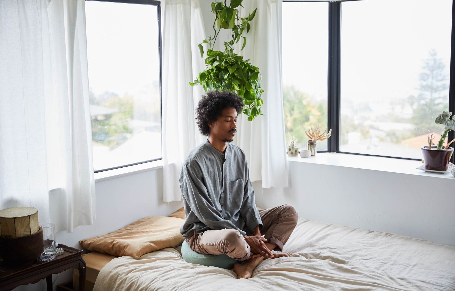 Young man sitting alone on his bed and meditating